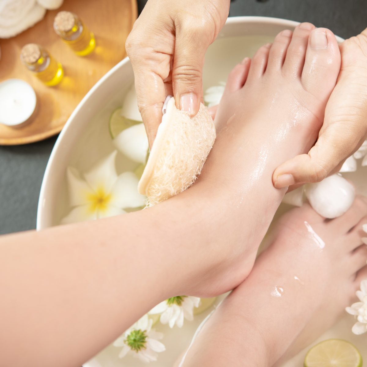 foot washing in spa before treatment. spa treatment and product foot washing in spa before treatment. spa treatment and product for female feet and hand spa. white flowers in ceramic bowl with water for aroma therapy at spa.